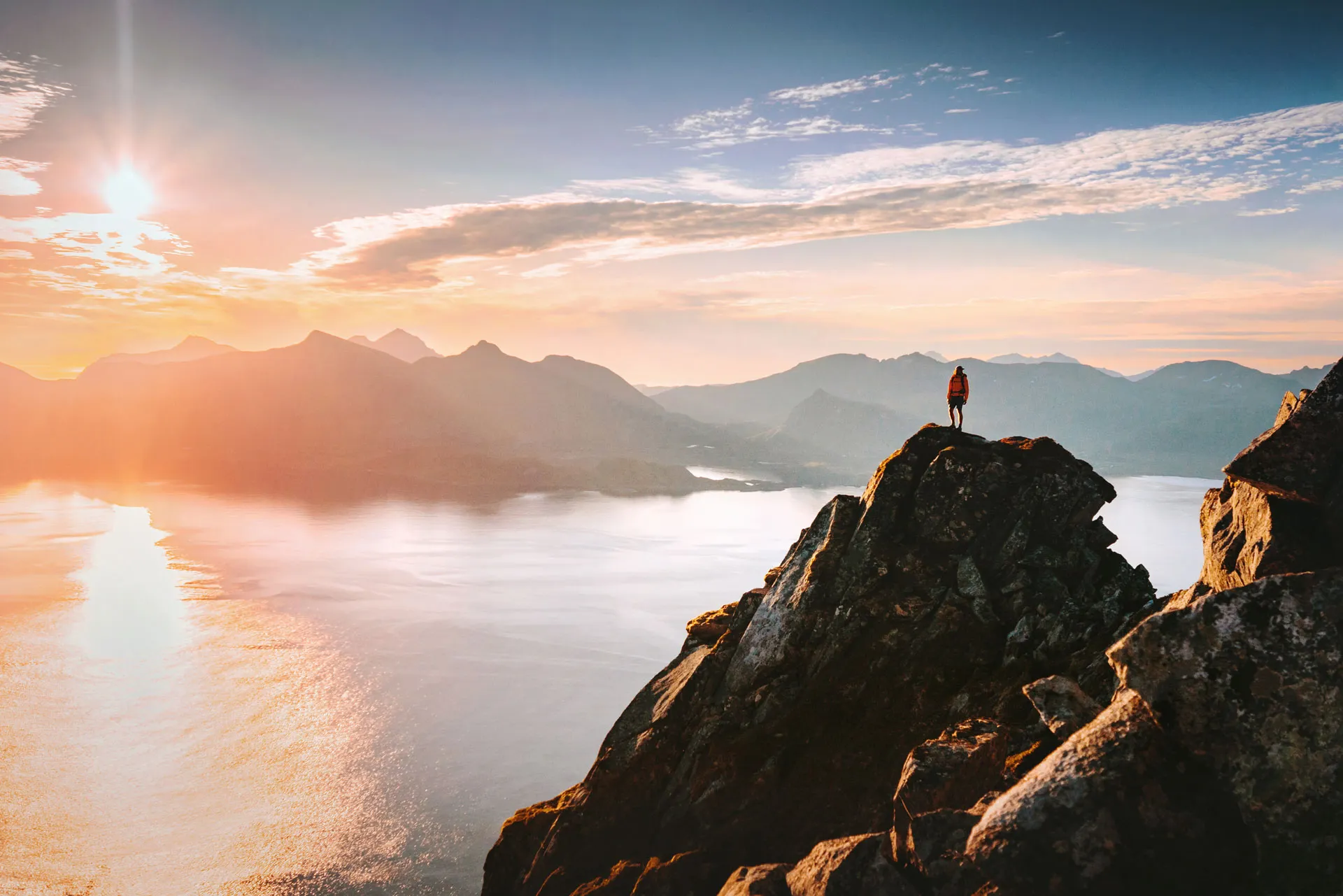 Person standing on mountain cliff overlooking a scenic landscape